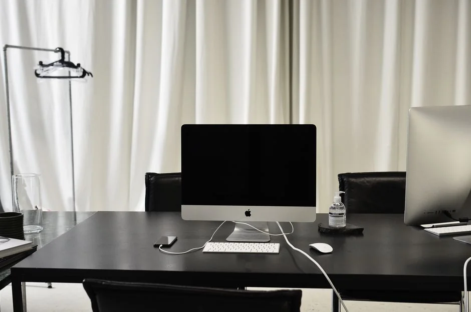 Vue en plongée d’un bureau de travail élégant avec deux écrans, un clavier, une souris et des accessoires modernes.